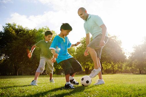 Hombre jugando fútbol con sus dos hijos