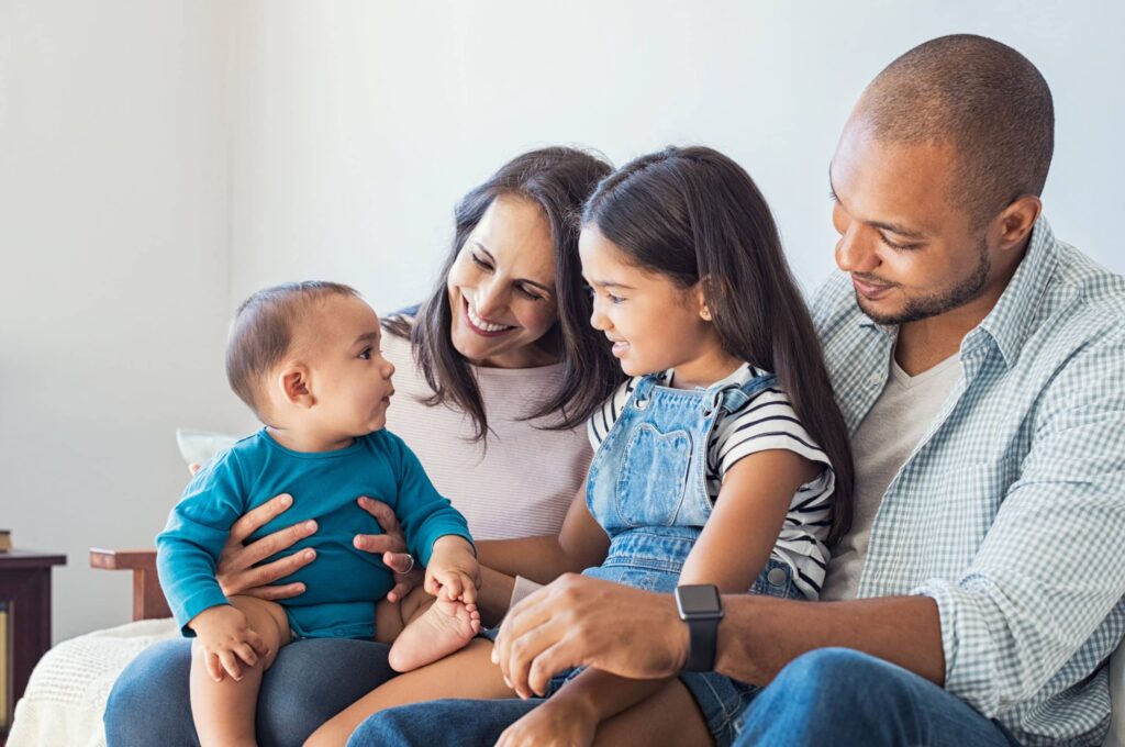 Bi-racial family sitting on couch smiling