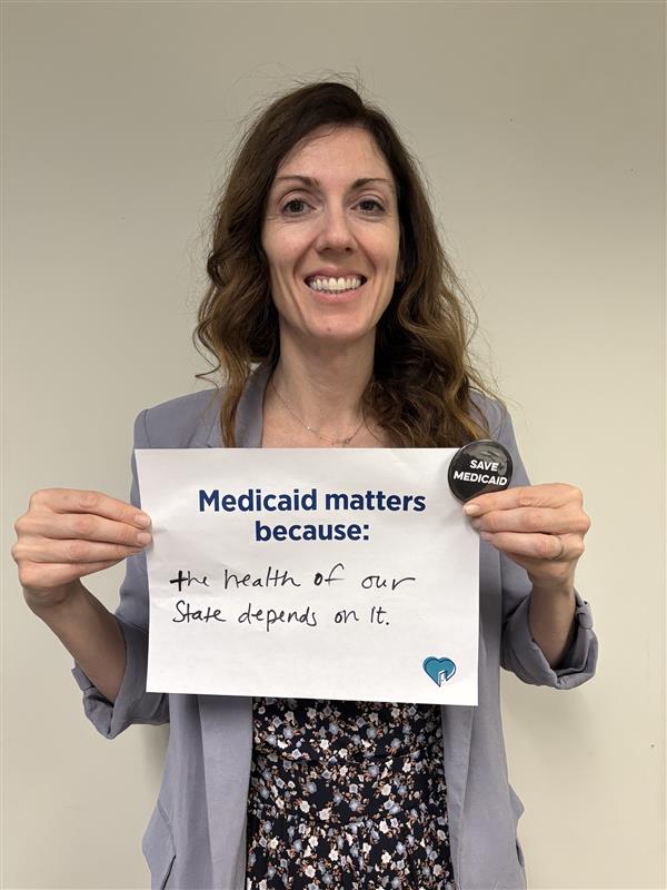 Woman holding "Medicaid Matters Because..." sign