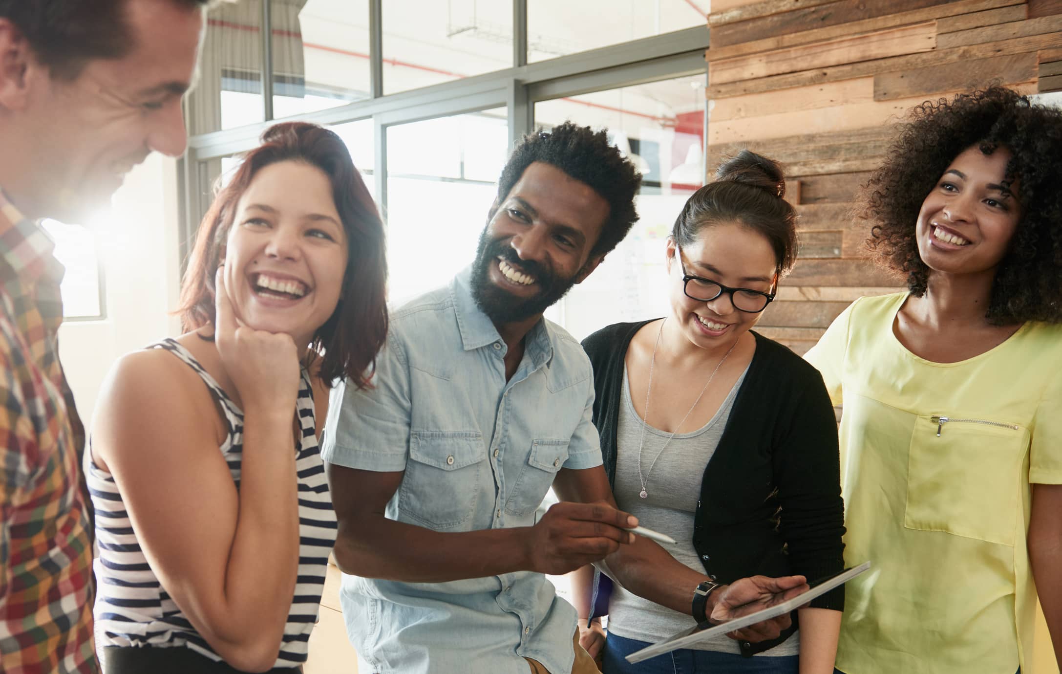 A diverse group of employees holding a meeting and looking at a tablet