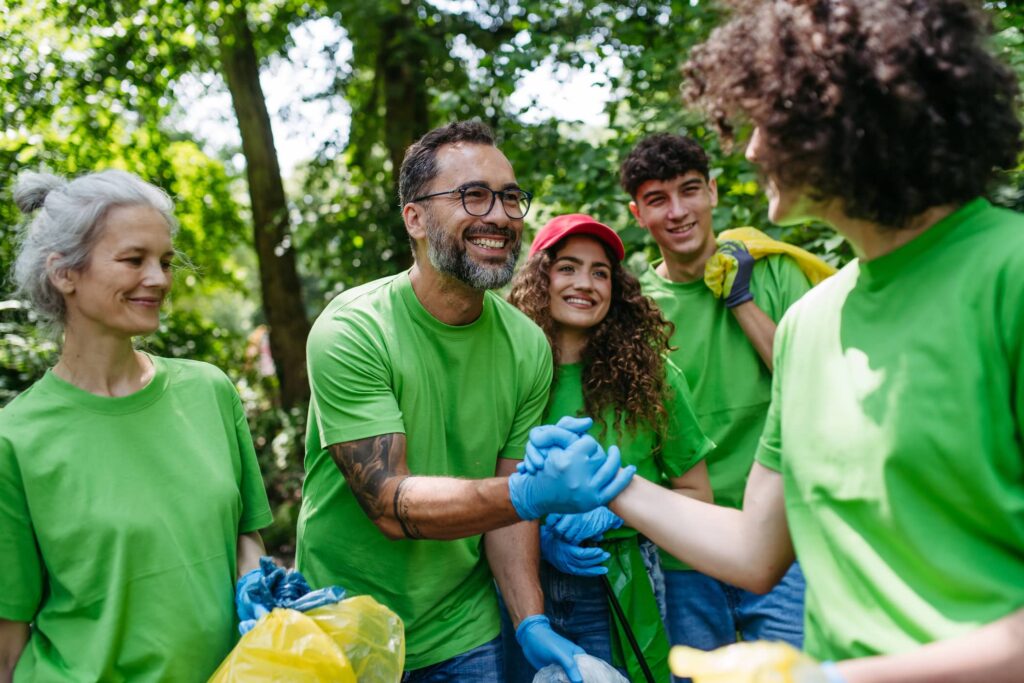 Group of people volunteering in the community with a man and woman shaking hands.