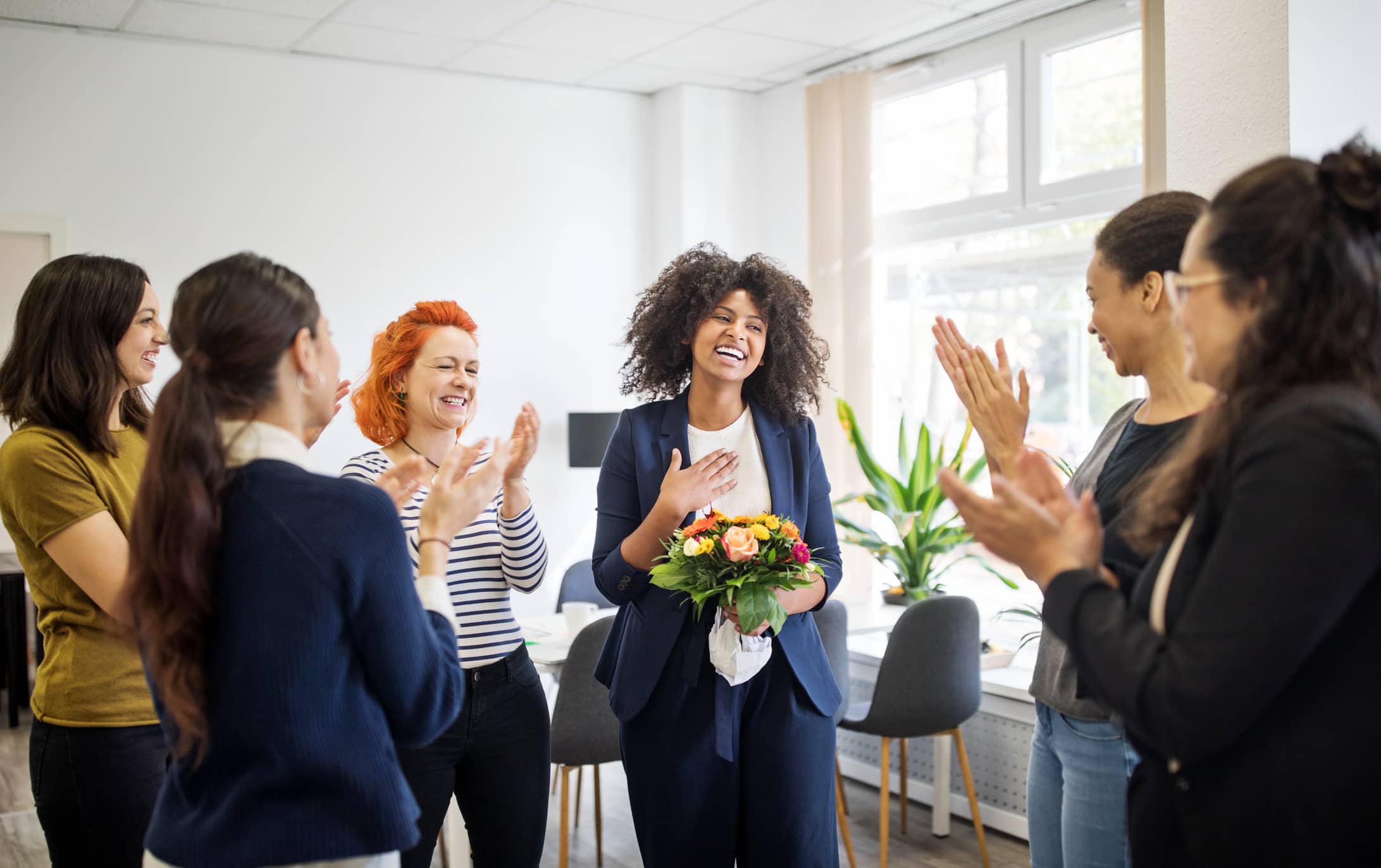 Group of women standing in a circle celebrating with flowers